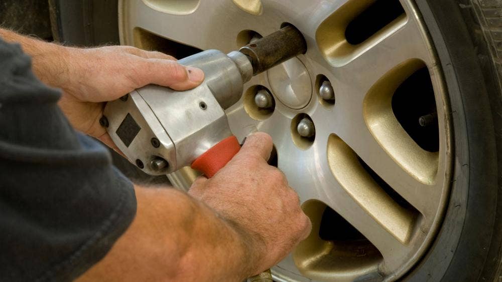 man using impact wrench on car wheel bolts