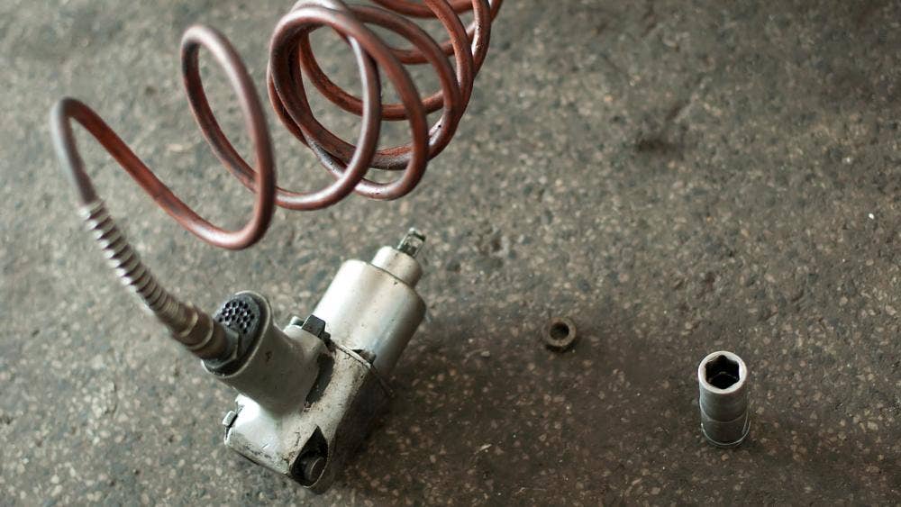 air impact wrench on floor with air cord coming out of handle