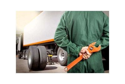 Man holding a spanner next to a truck
